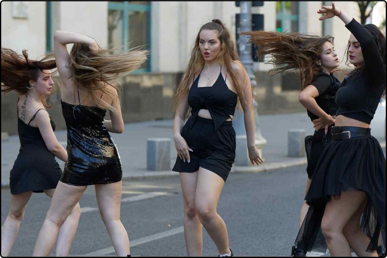 Group of women joyfully dancing together on a city street.